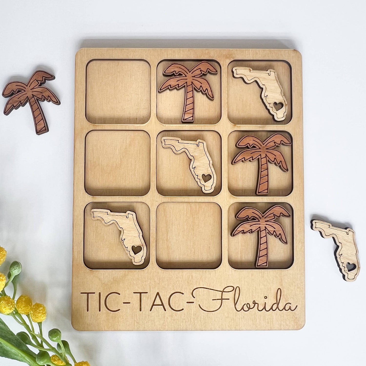 Wooden tic-tac-toe board with Florida and palm tree shapes on a white background