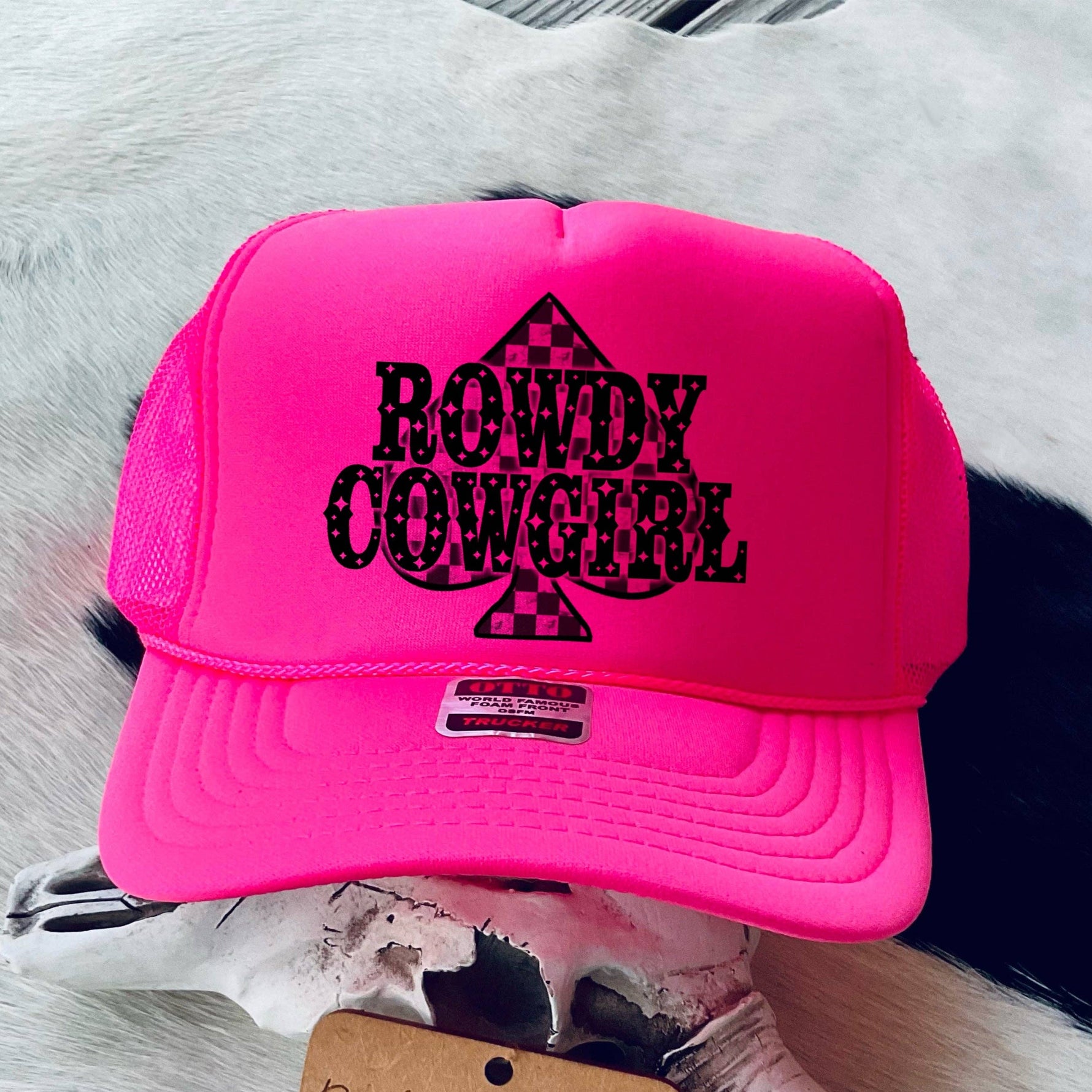 Pink cap with 'Rowdy Cowgirl' text on a cowhide background