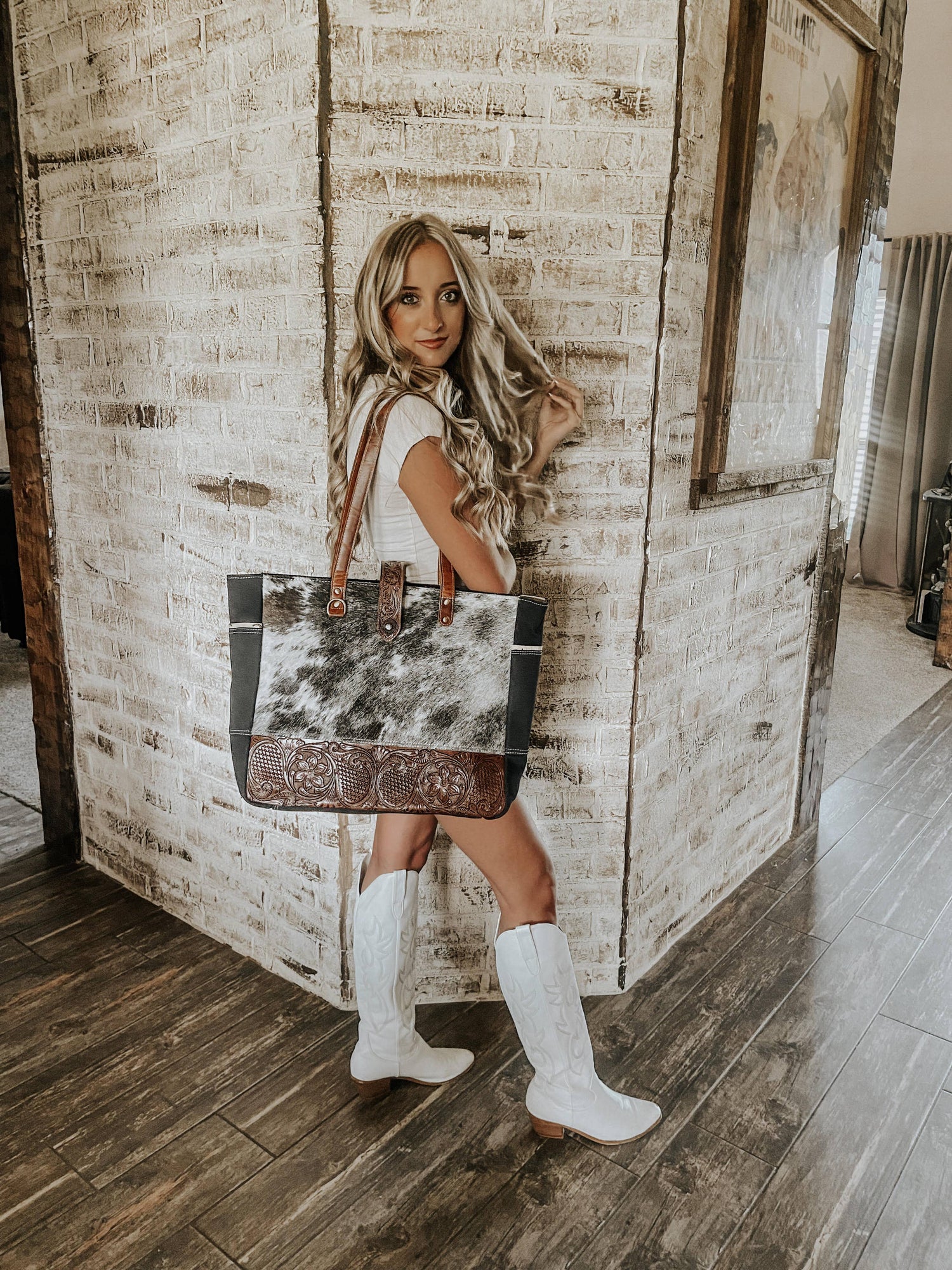 Woman holding a cowhide bag in a rustic interior setting