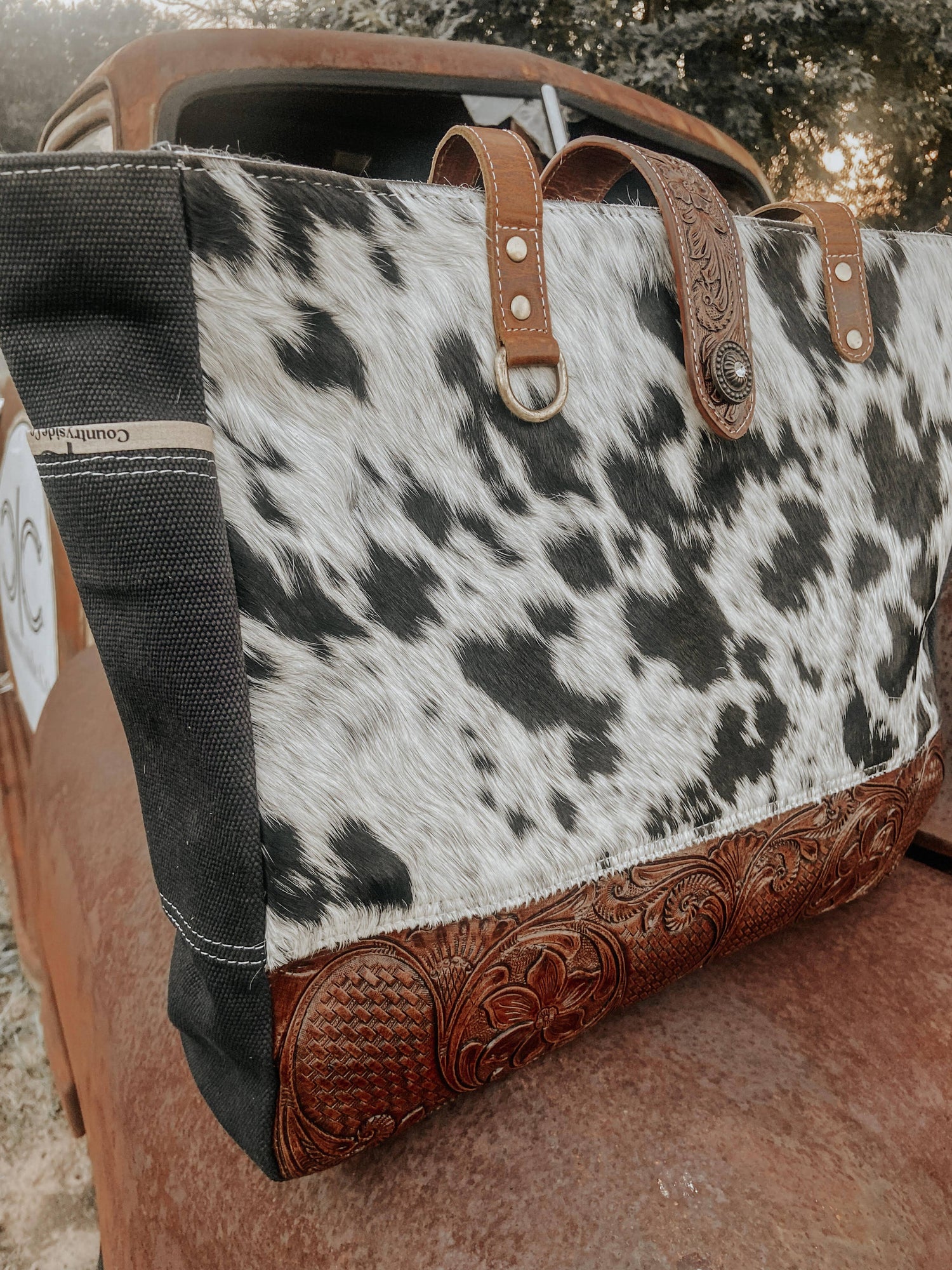 Cowhide leather bag with decorative handle and stitching on a textured surface