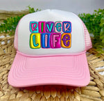 Pink and white cap with 'River Life' text in colorful letters on a woven surface.
