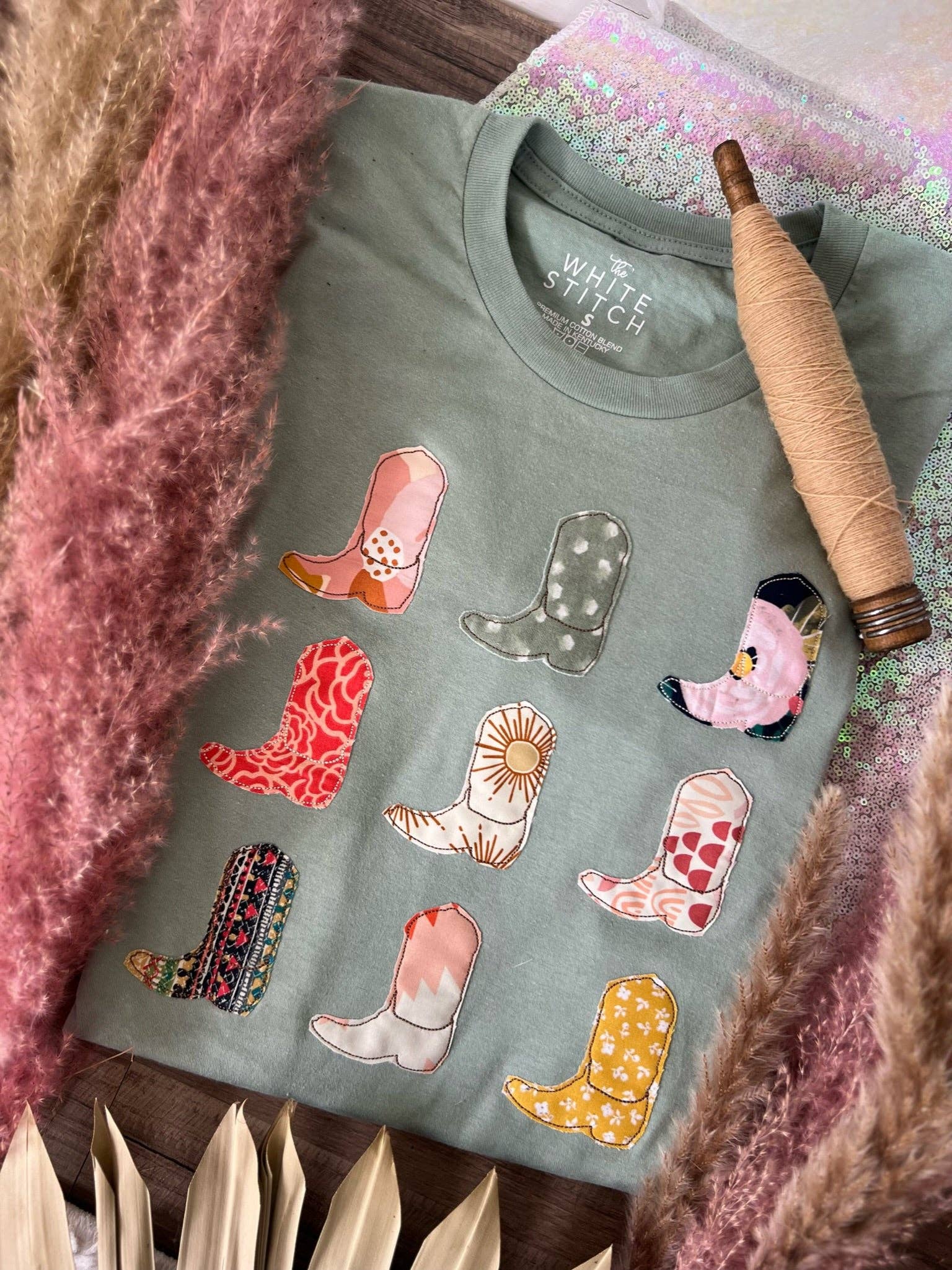 Green sweatshirt with colorful cowboy boot patches on a textured surface