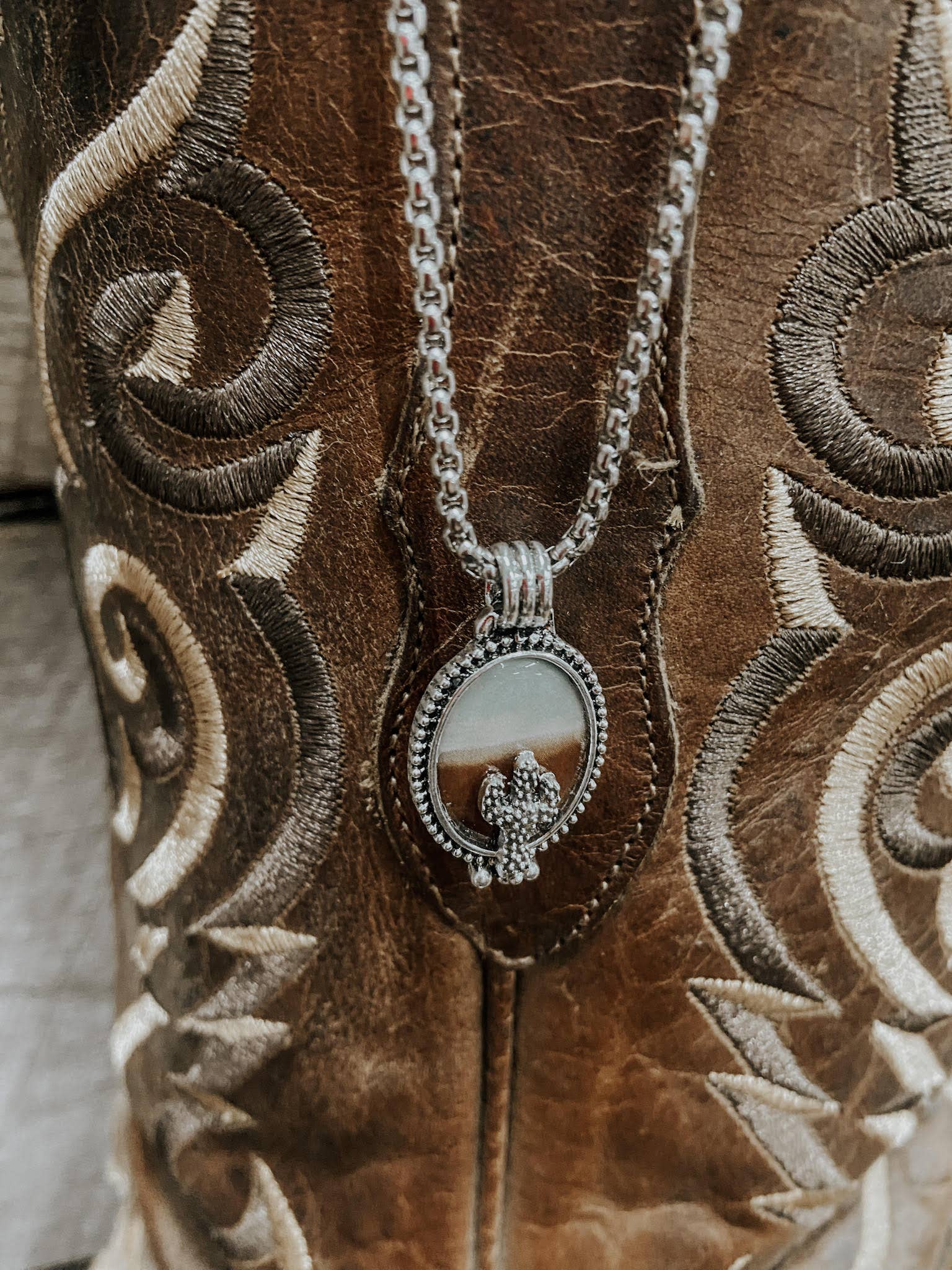 Silver necklace with a pendant on a brown embroidered surface