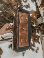 Handbag with brown leather embossed panels on a cowhide rug