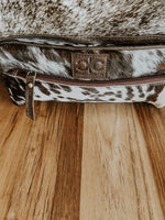 Cowhide leather bag with a visible brand logo on a wooden surface