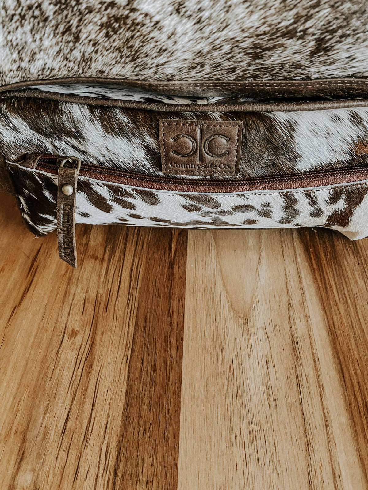 Cowhide leather bag with a visible brand logo on a wooden surface