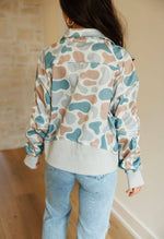Person wearing a colorful patterned jacket and light blue jeans indoors.