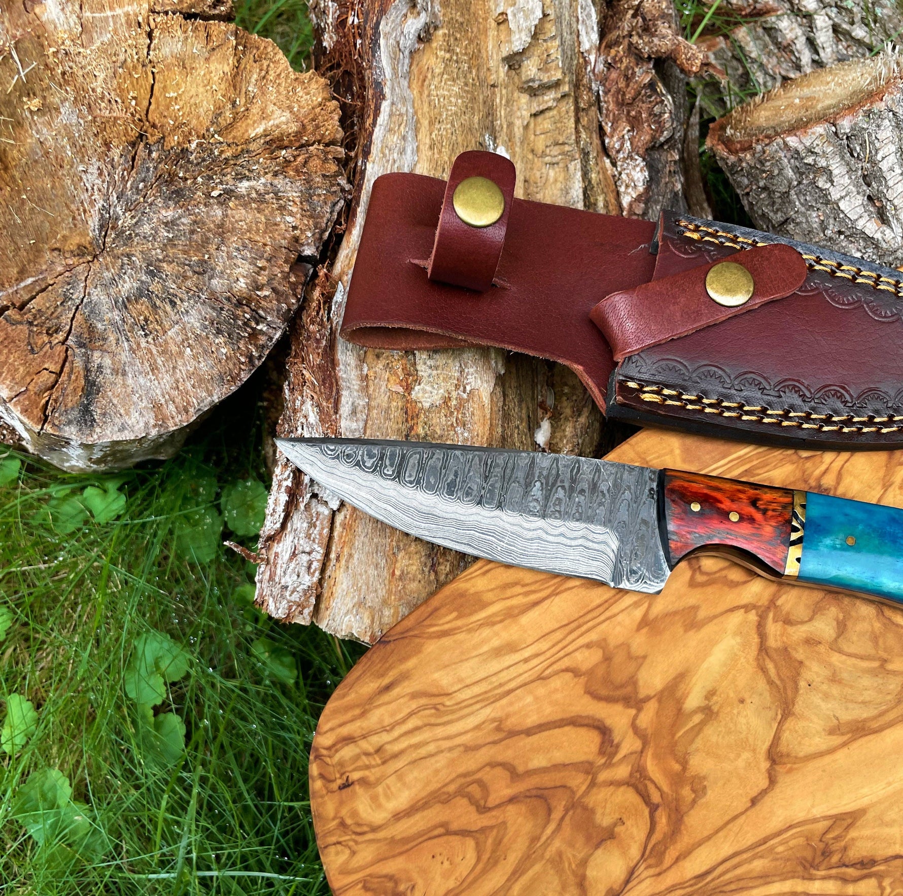 Knife with a wooden handle and leather sheath on a wooden surface