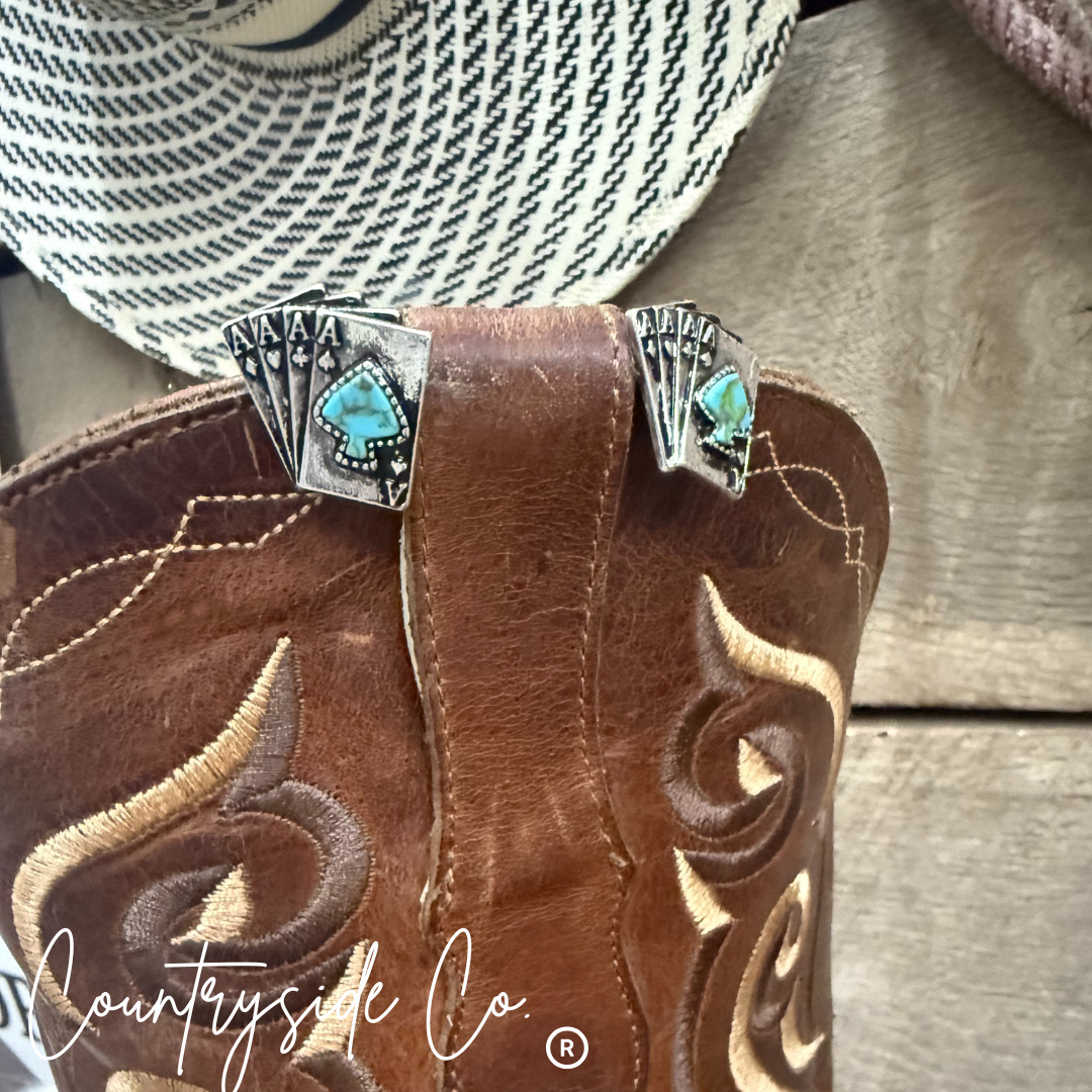 Brown cowboy boot with decorative buckle featuring turquoise stones on a wooden surface, branded 'Countryside Co'.