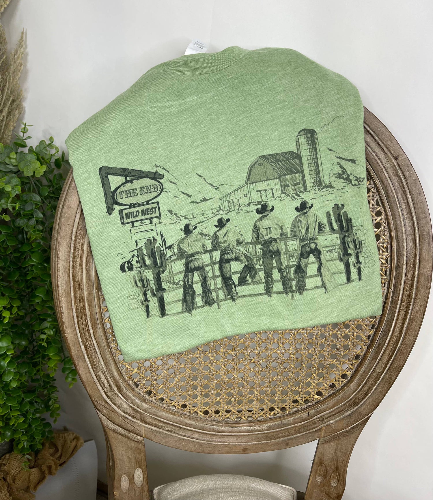 Green t-shirt with a cowboy graphic on a wooden chair