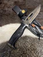 Decorative knife with a black handle and detailed blade on a fur background