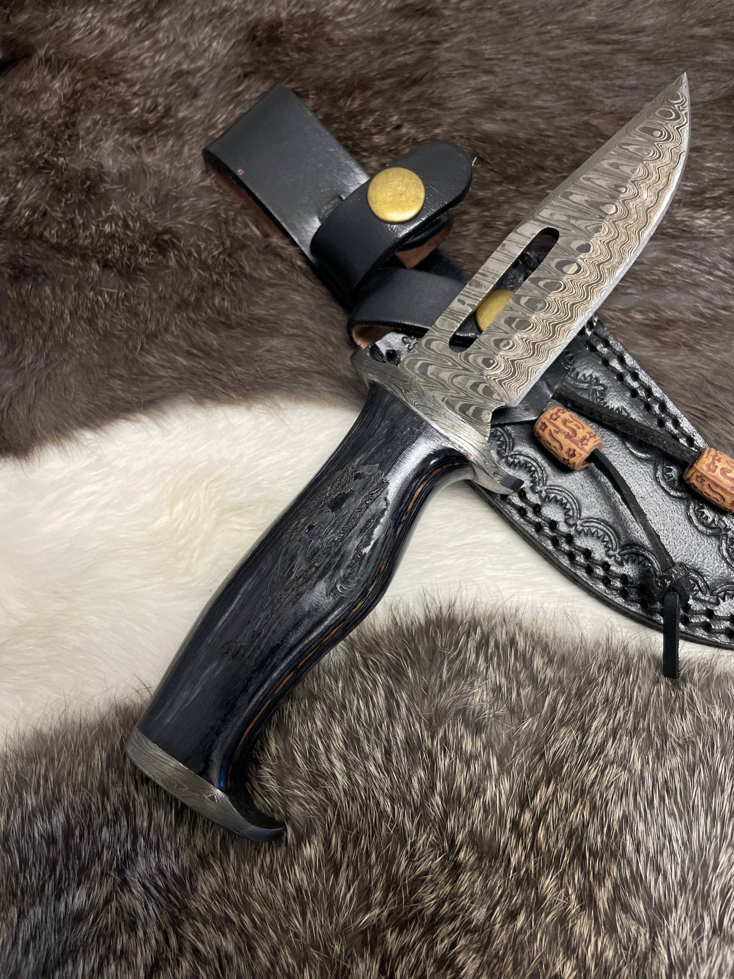 Decorative knife with a black handle and detailed blade on a fur background