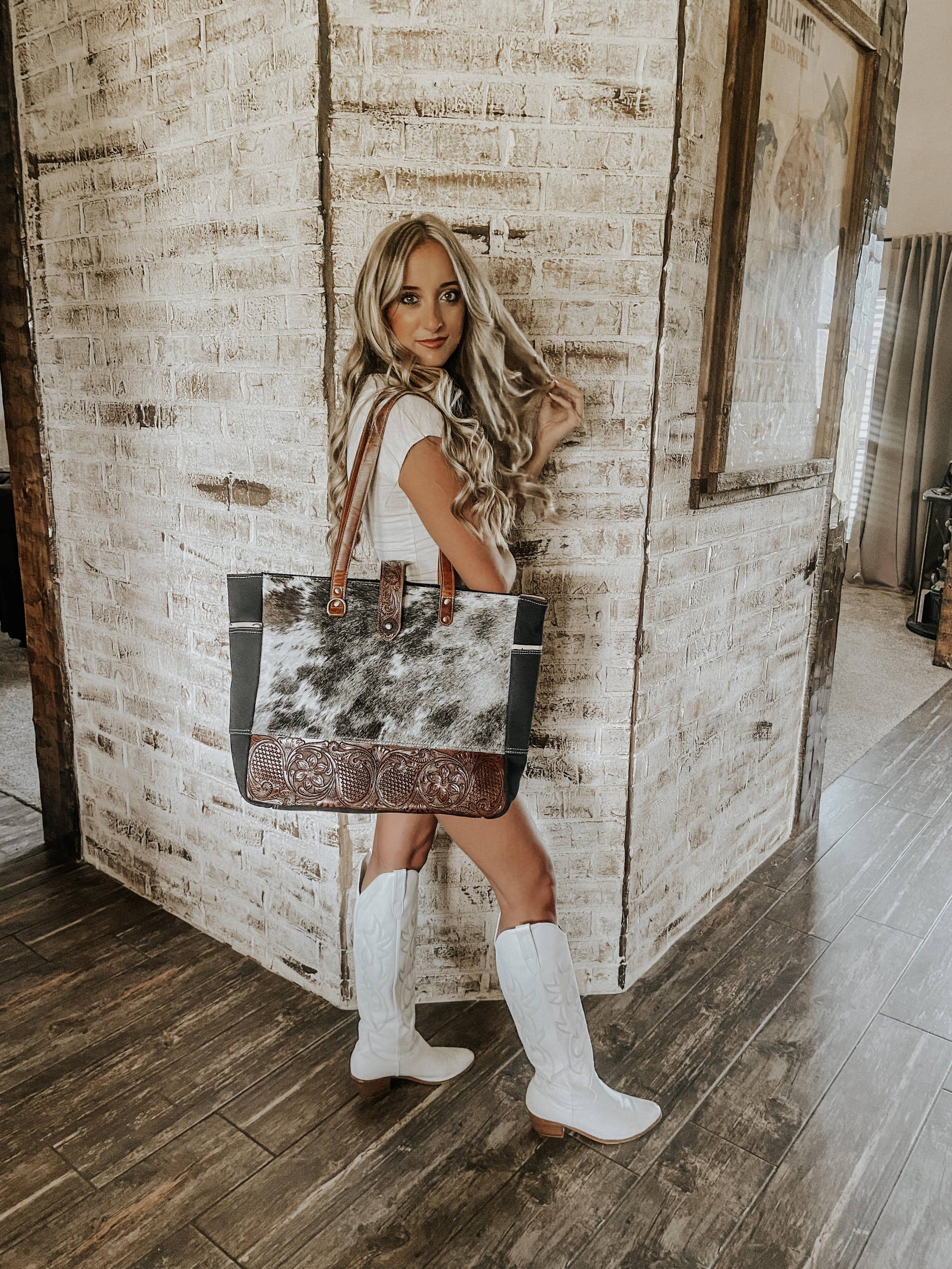 Woman holding a cowhide bag in a rustic interior setting