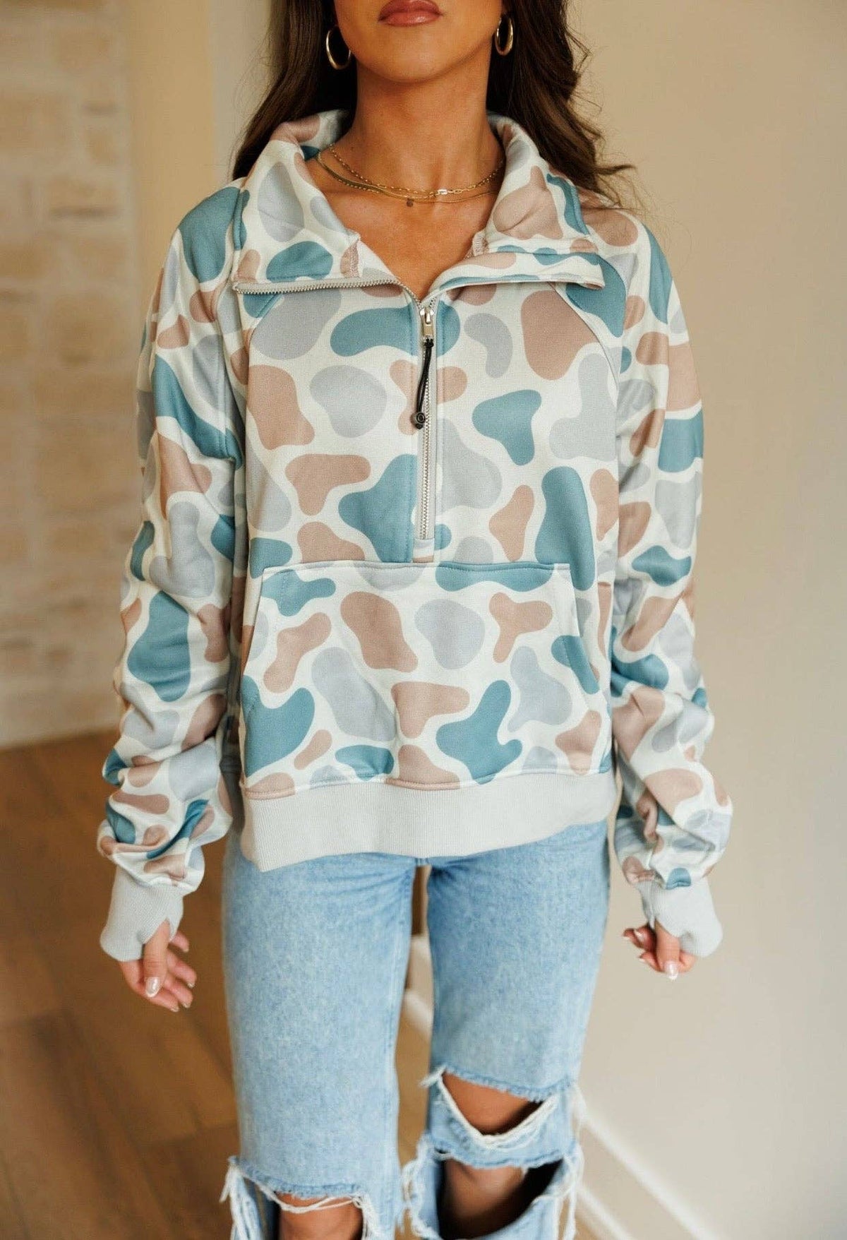 Person wearing a patterned pullover and ripped jeans indoors