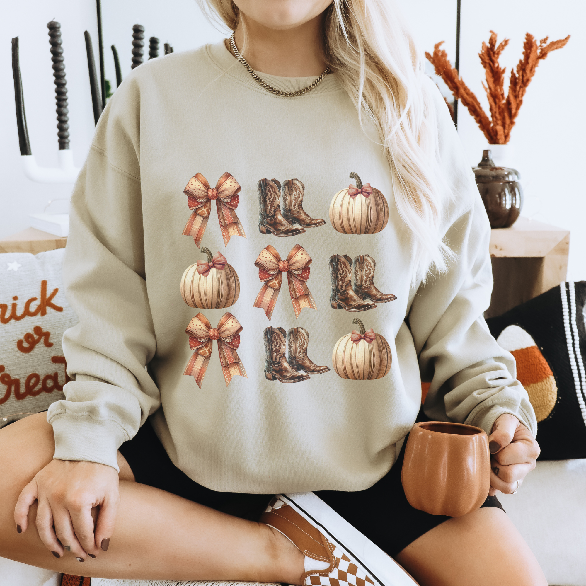 Person wearing a beige sweatshirt with autumn-themed designs, sitting on a couch.