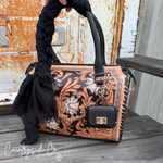 Handbag with intricate designs and a keychain on a wooden surface, featuring the 'Countryside Co' brand.