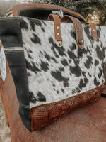 Cowhide leather bag with decorative handle and stitching on a textured surface