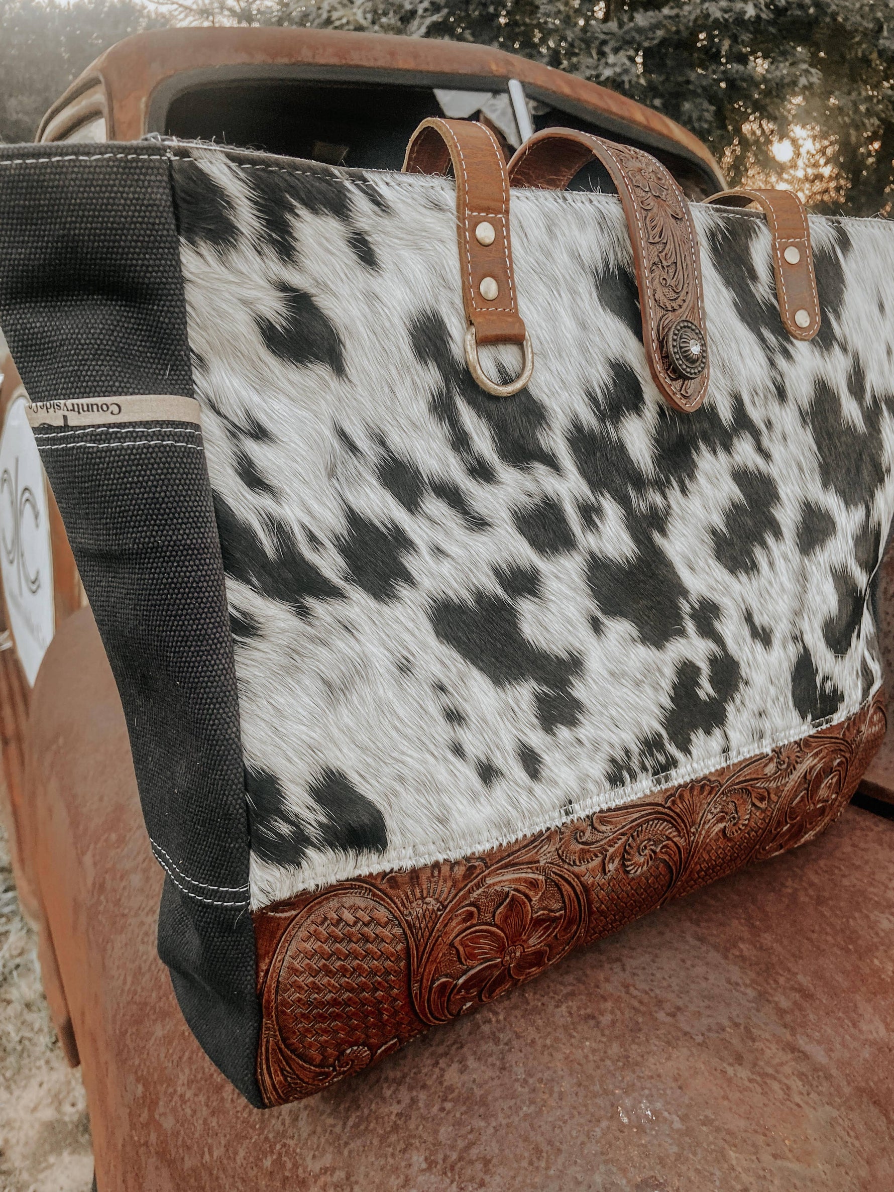 Cowhide leather bag with decorative handle and stitching on a textured surface