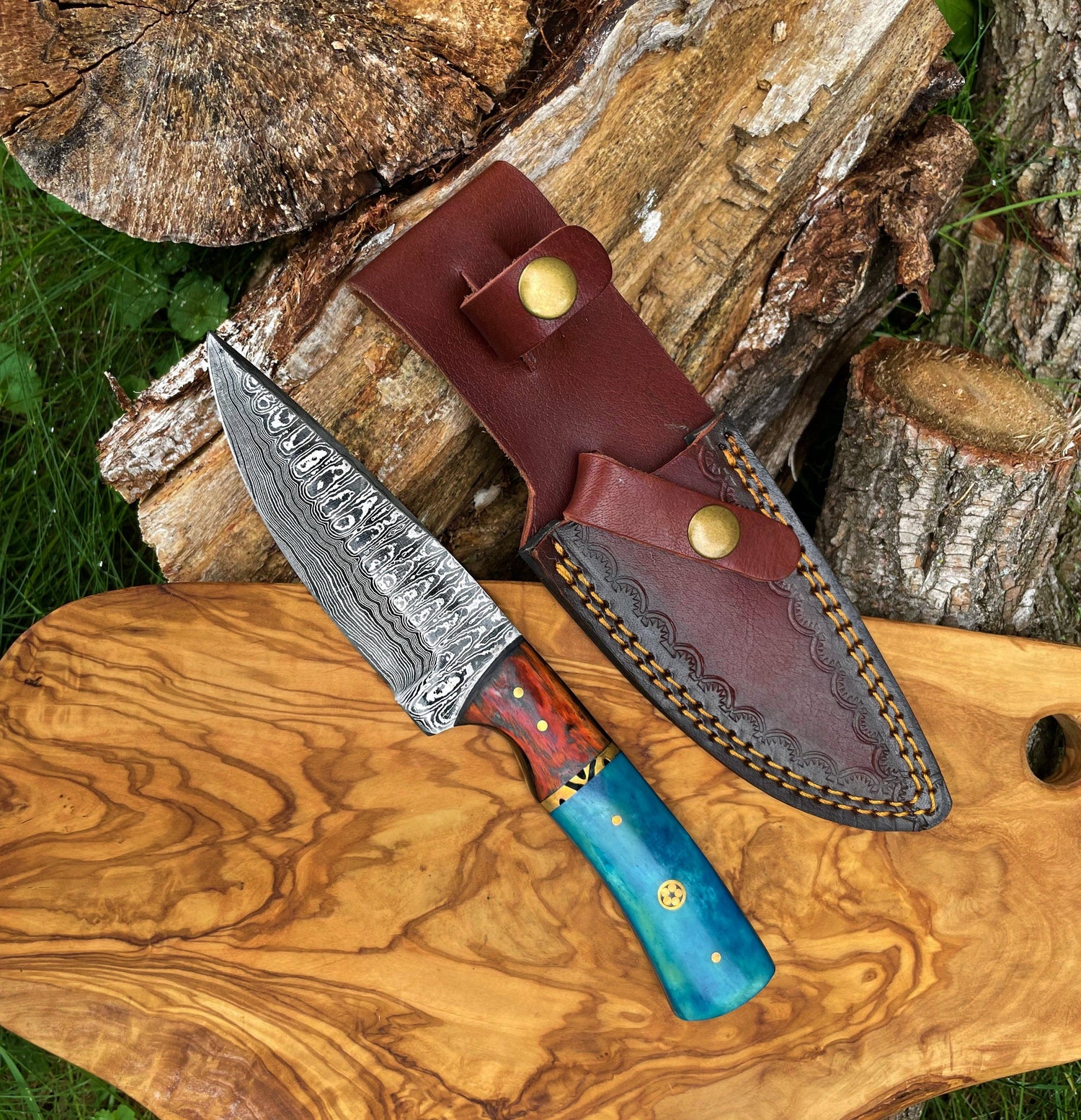 Decorative knife with a blue handle and leather sheath on a wooden surface