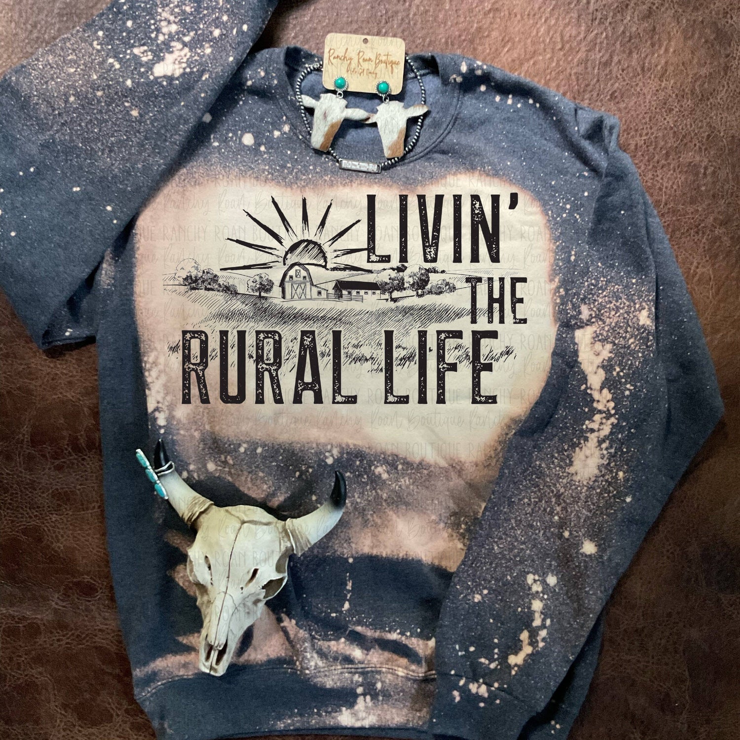 Sweatshirt with 'Livin' the Rural Life' graphic design on a textured surface