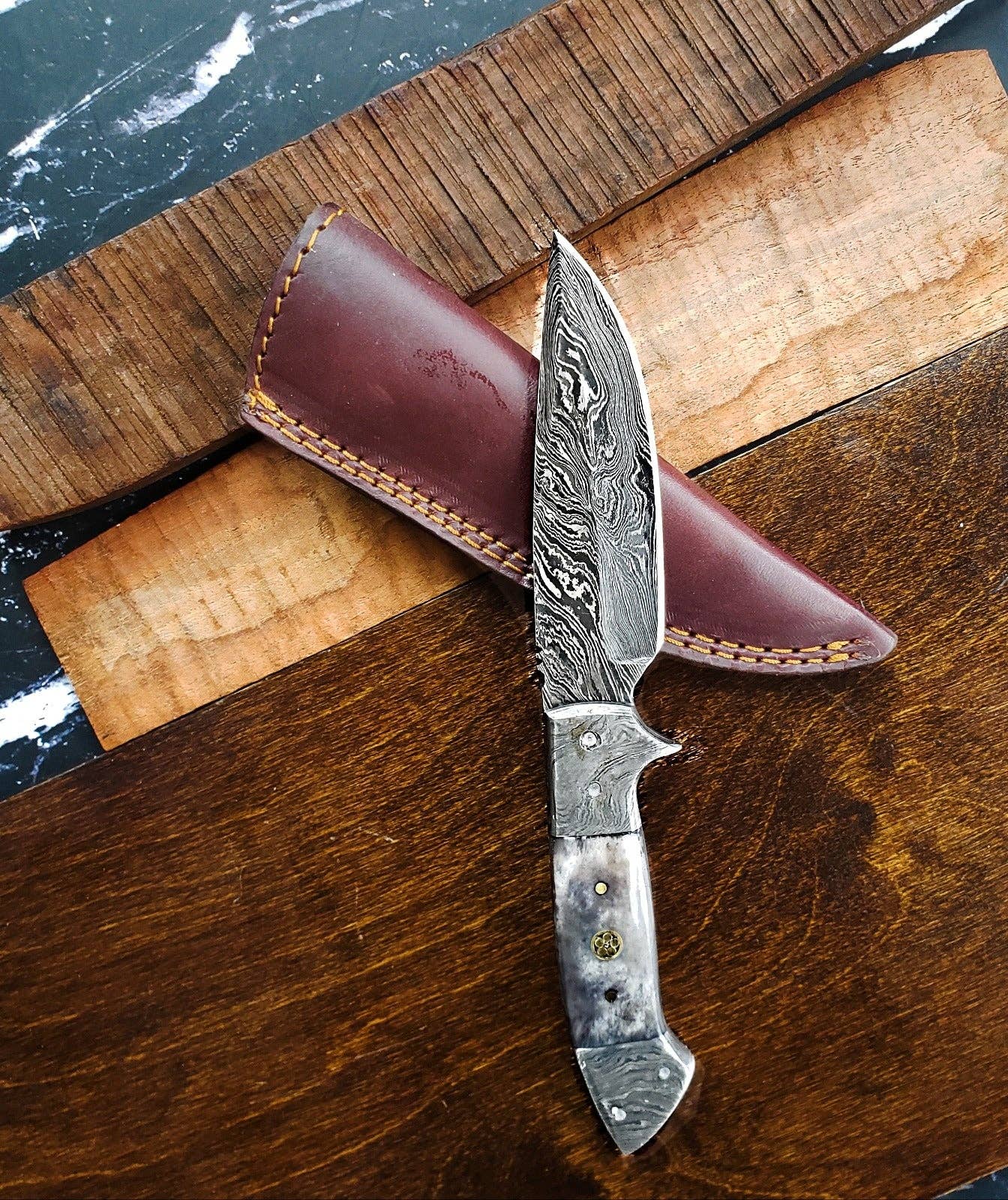 Decorative knife with a leather sheath on a wooden surface