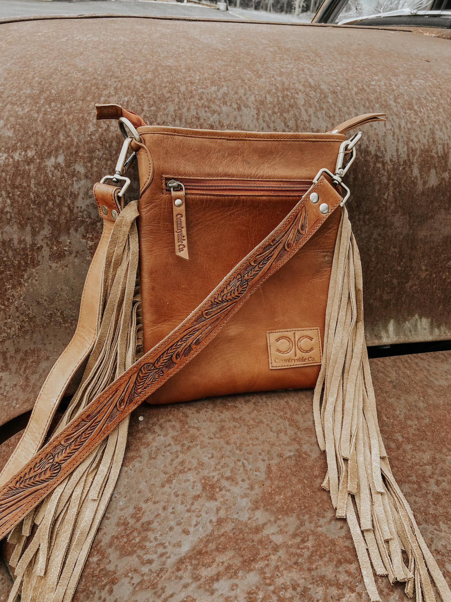 Brown leather handbag with fringes on a textured surface