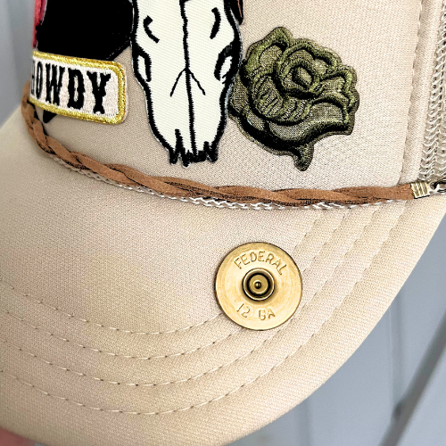 Beige cap with cowboy patch, skull design, and green rose on a light blue background