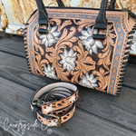 Handbag with floral tooled design on a wooden surface, featuring the 'Countryside Co' brand.