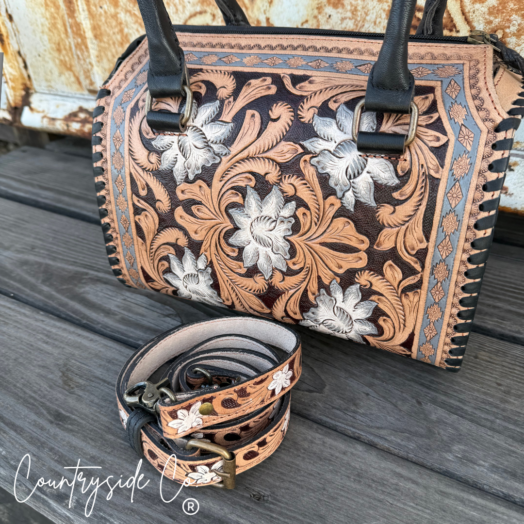 Handbag with floral tooled design on a wooden surface, featuring the 'Countryside Co' brand.