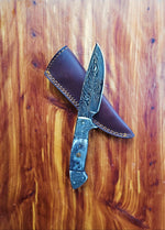 Decorative knife with a leather sheath on a wooden surface