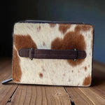Cowhide leather wallet with brown strap on a wooden surface