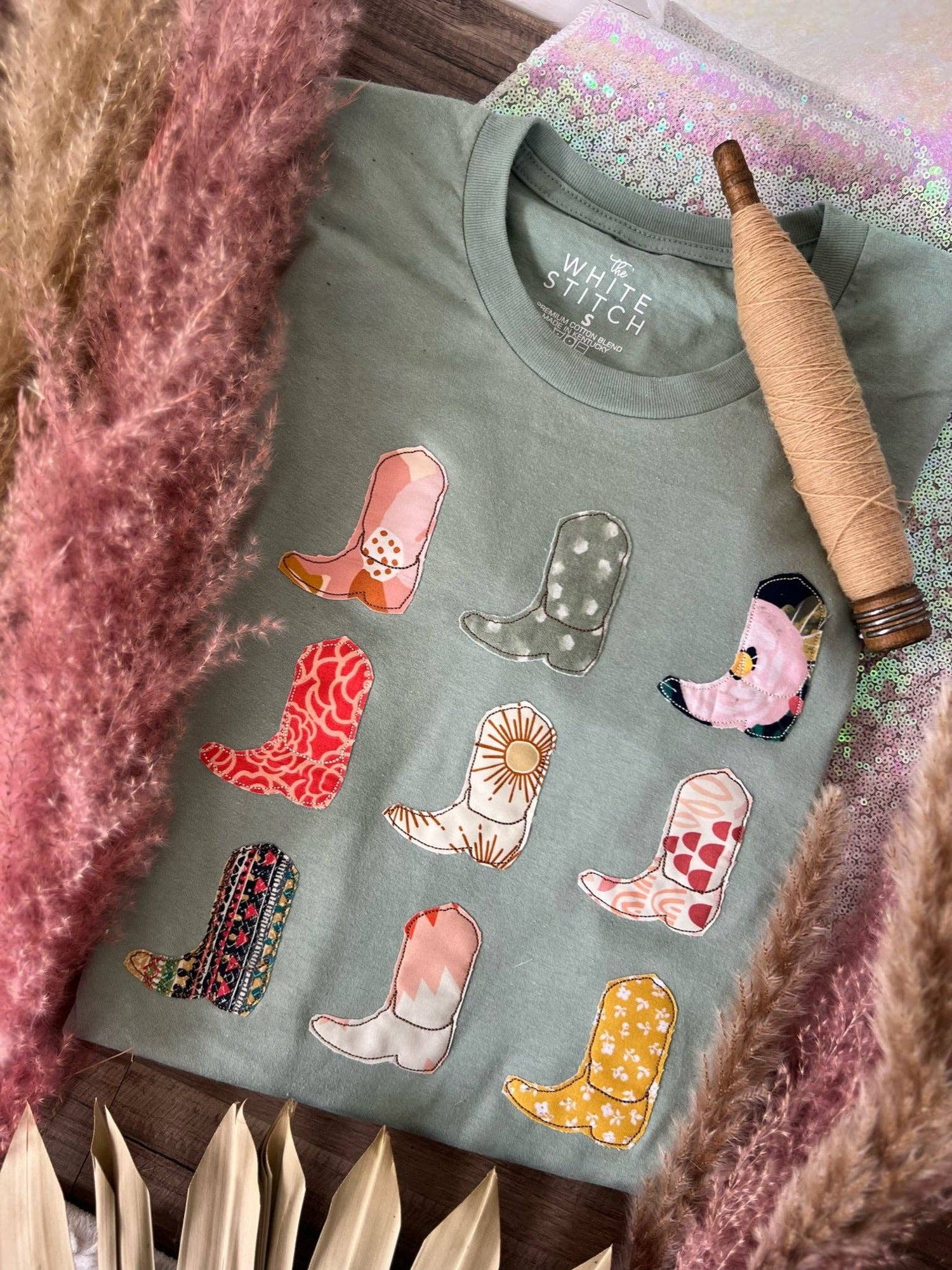 Green sweatshirt with colorful cowboy boot patches on a textured surface