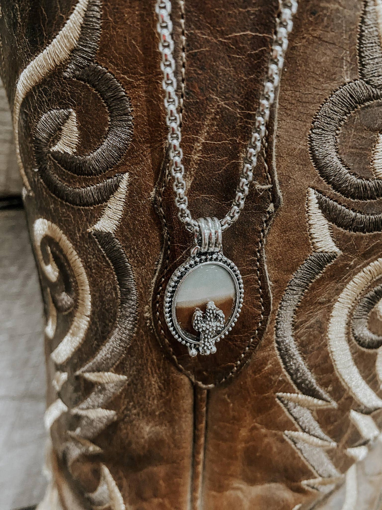 Silver necklace with a pendant on a brown embroidered surface
