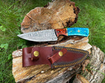 Knife with a blue handle and brown leather sheath on a wooden log